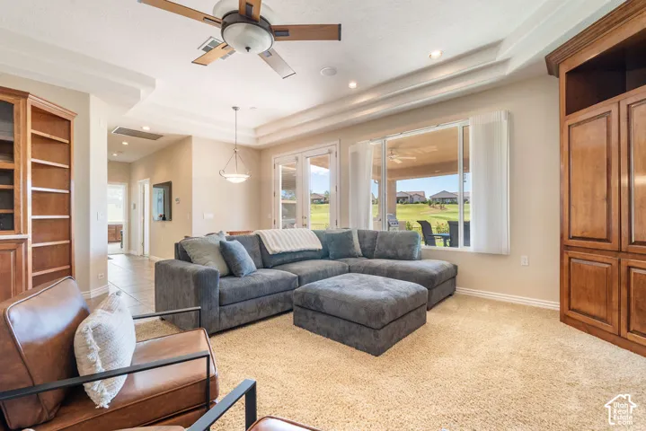 Living area featuring a tray ceiling, ceiling fan, recessed lighting, and built-in cabinetry