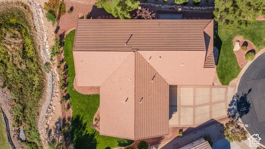 Terracotta tile roofing, expansive paved driveway, manicured green lawn, and mature perimeter landscaping