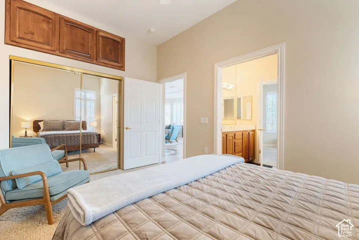 Vaulted ceiling, mirrored closet doors, rich wood-finish cabinetry, and neutral wall tones