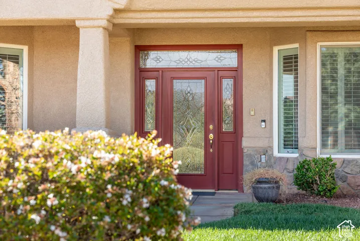 Stucco exterior with stone accents, a deep red entry door with decorative glass, and a transom window