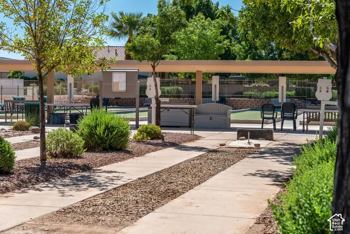 Concrete pathways with gravel accents, mature landscaping, covered outdoor area, bocce ball court, and a white information board
