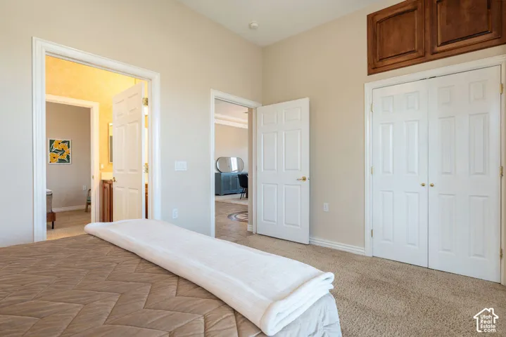 Beige wall paint, textured carpet flooring, wood-finish overhead cabinetry, white paneled doors, and a vaulted ceiling