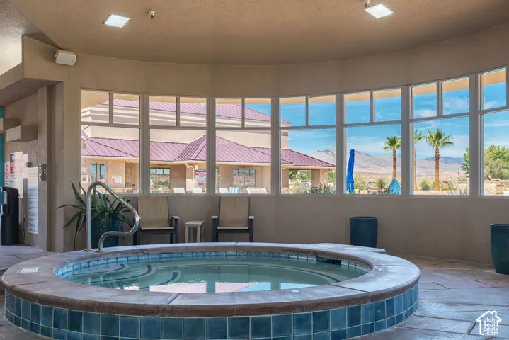 Indoor spa with tile surround, curved window wall, recessed lighting, and stamped concrete flooring