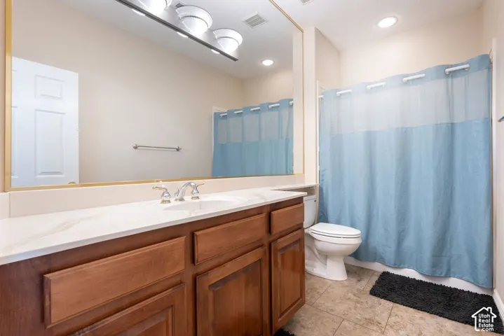 Bathroom featuring a single vanity with wood cabinetry, a large mirror, a white countertop, and a shower/tub combination