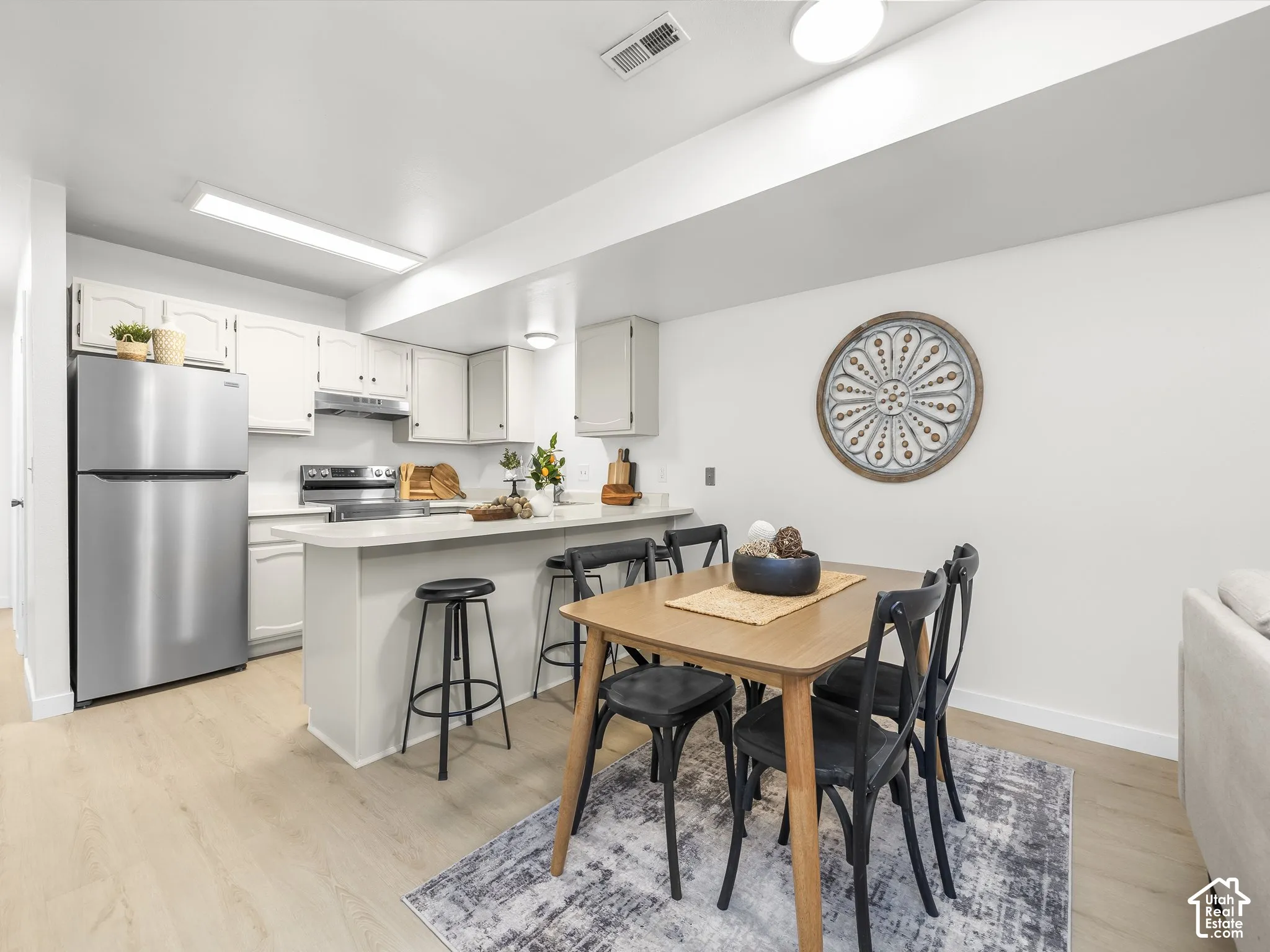 Kitchen featuring stainless steel appliances, light-toned cabinetry, and a peninsula with seating