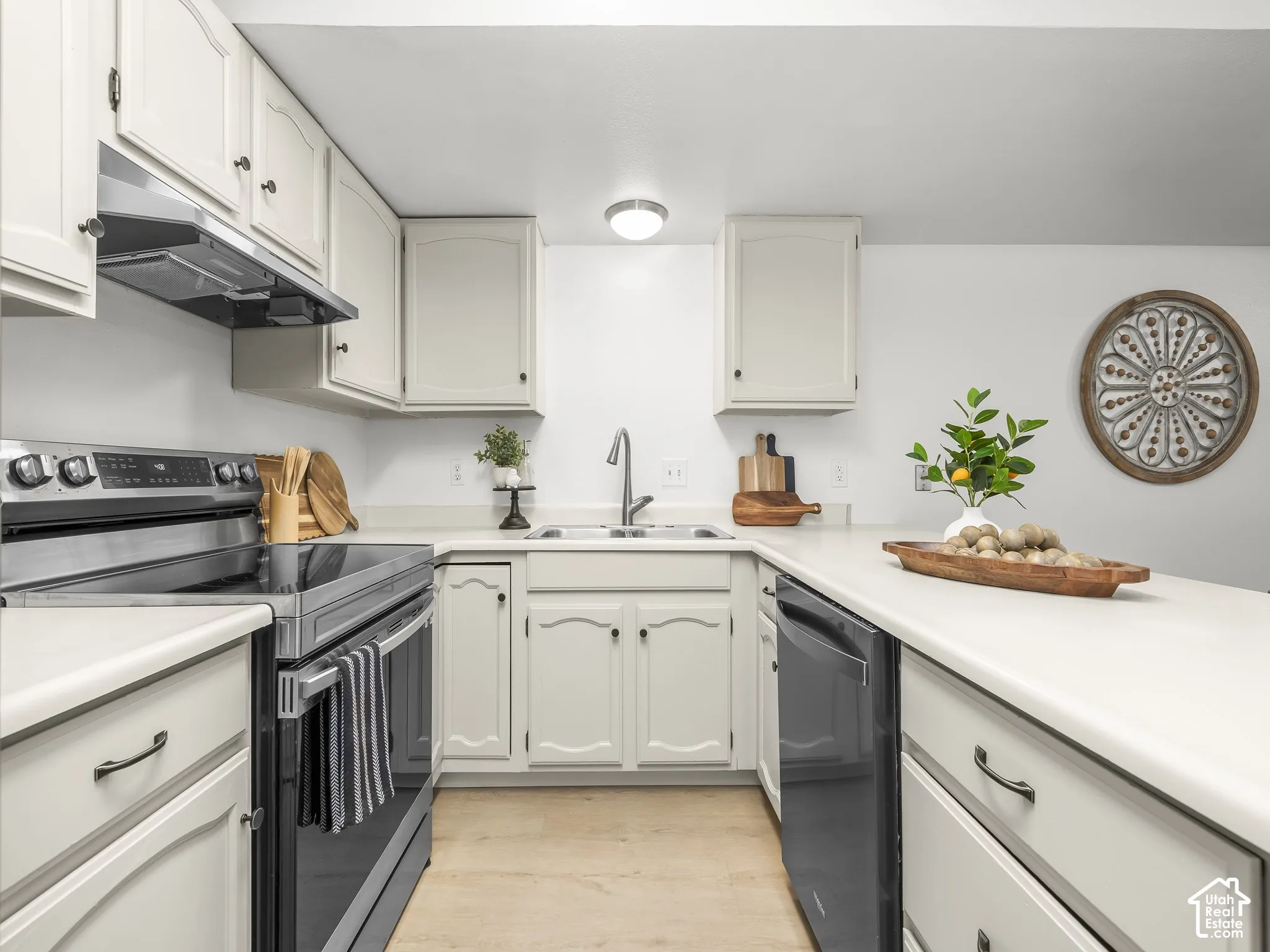 U-shaped kitchen featuring cream cabinetry, light-toned countertops, and a stainless-steel electric range
