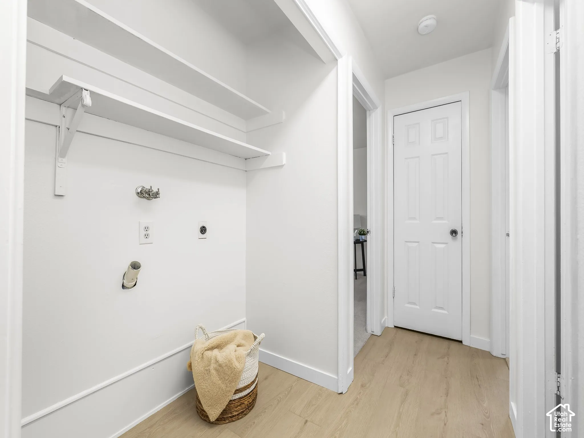 Built-in laundry hookups with upper shelving, wood-finish flooring, and white interior doors