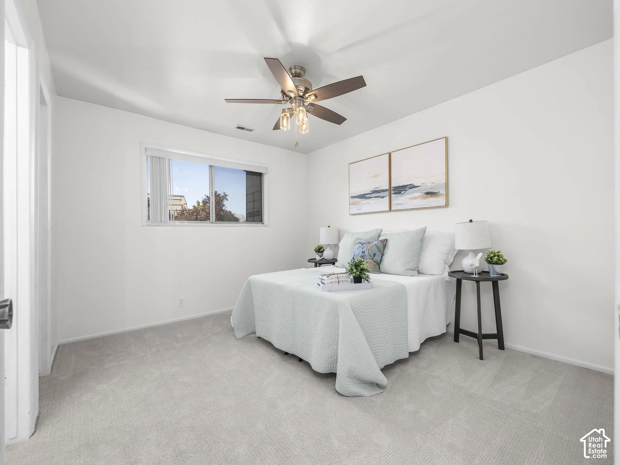 Recessed window with white trim, light-colored carpet flooring, white walls, and a ceiling fan with light fixture