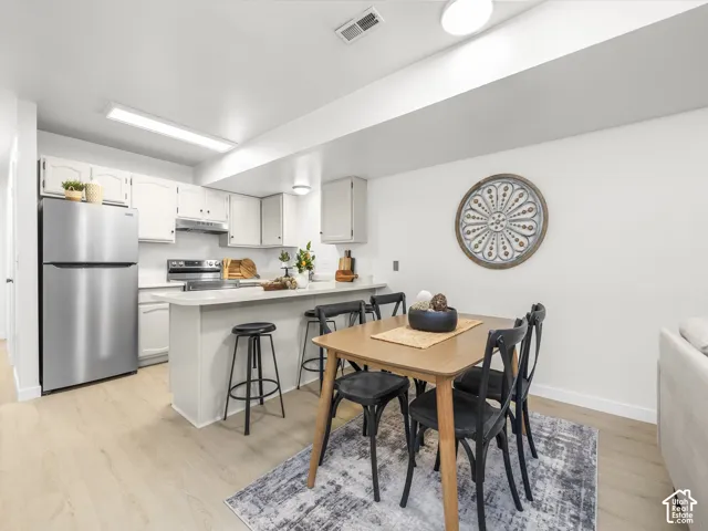 Kitchen featuring stainless steel appliances, light-toned cabinetry, and a peninsula with seating