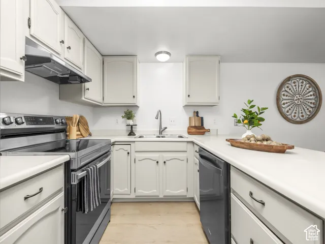 U-shaped kitchen featuring cream cabinetry, light-toned countertops, and a stainless-steel electric range