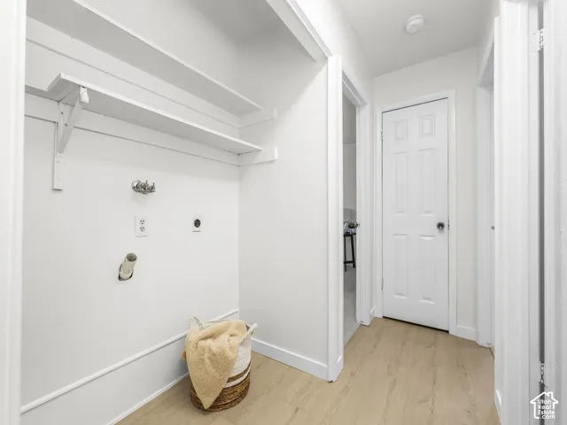 Built-in laundry hookups with upper shelving, wood-finish flooring, and white interior doors