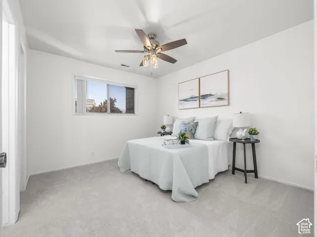Recessed window with white trim, light-colored carpet flooring, white walls, and a ceiling fan with light fixture