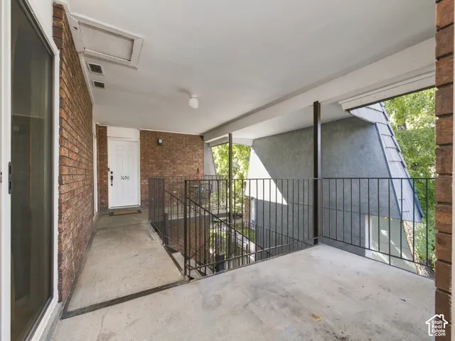 Covered concrete balcony with brick exterior wall and black metal railings