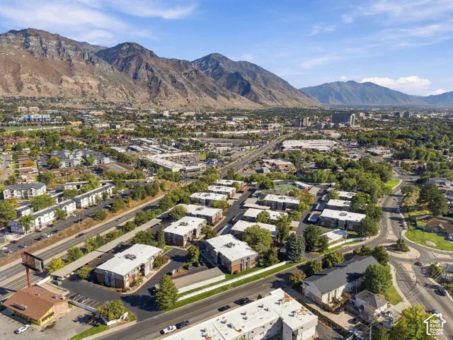 Urban landscape with surrounding mountains, visible residential buildings, mature trees, and a developed road network