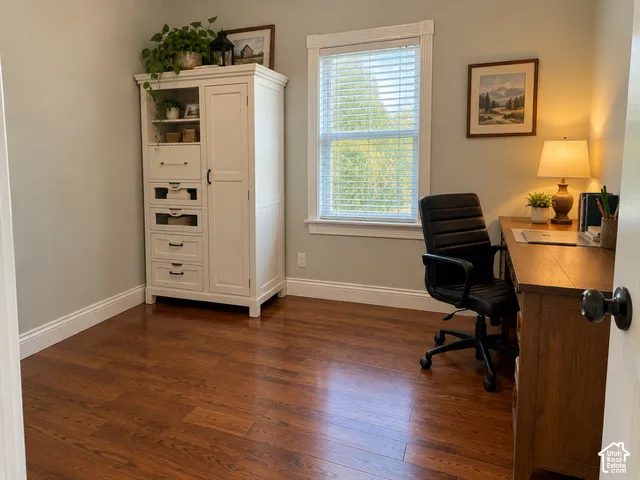 Room with wood-finish flooring, white trim, and a built-in window with white blinds