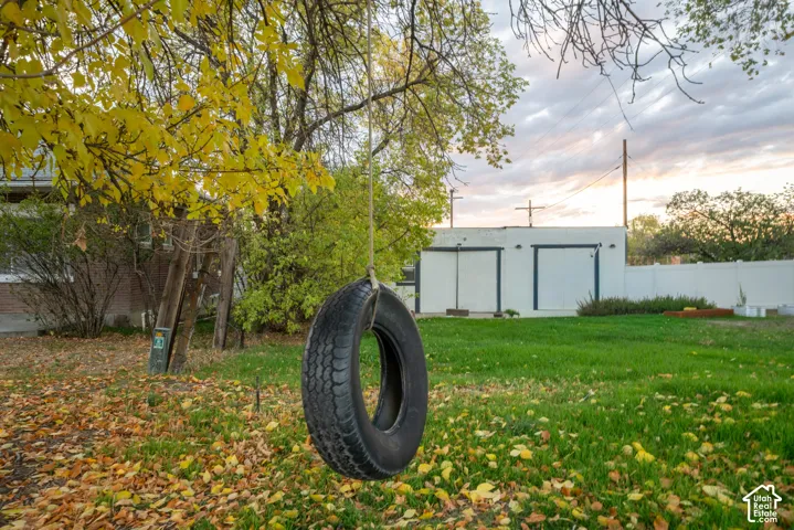 Backyard featuring a grass lawn, mature trees, and an exterior storage building with a white finish