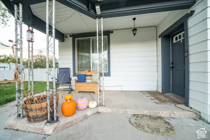 Covered porch featuring concrete flooring, horizontal siding, and decorative metal support pillars