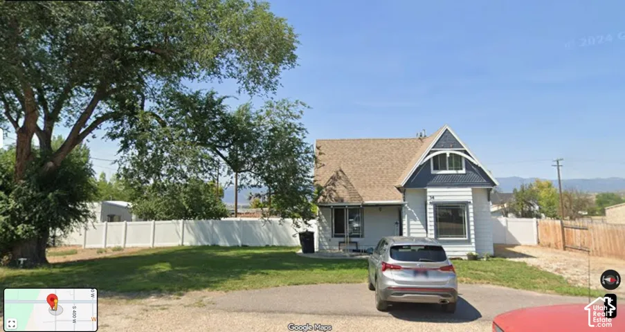 White siding exterior with a dark blue gable accent, brown shingle roofing, and a prominent front-facing window