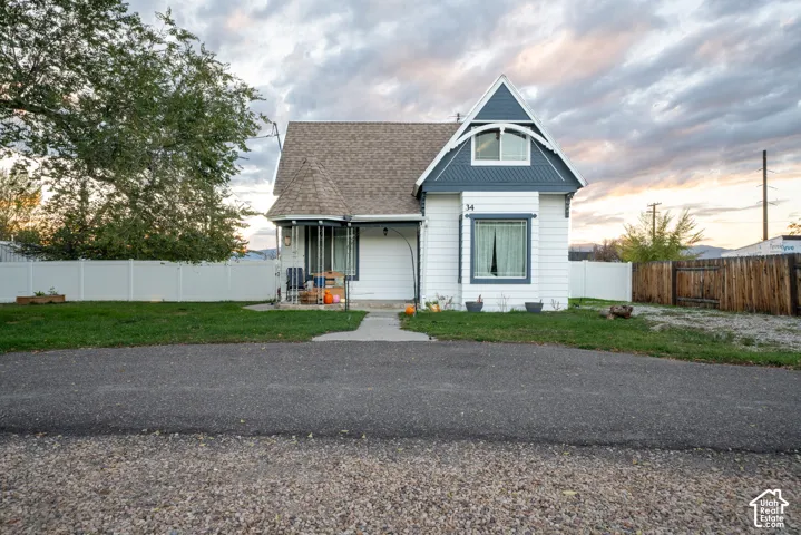 Exterior facade featuring white horizontal siding, blue decorative shingle gables, a covered front porch, and arch-top window detailing
