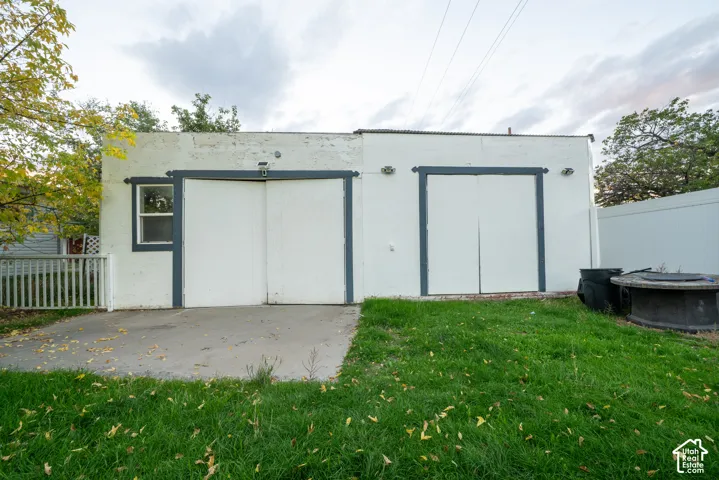 HUGE Detached garage with tons of storage.  white stucco siding, two sets of double-door entry points, and a concrete patio
