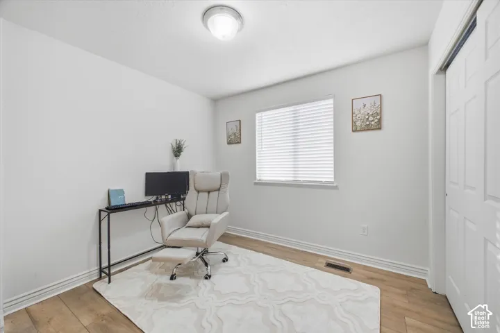 Wood-finish flooring, white walls, and a window with blinds