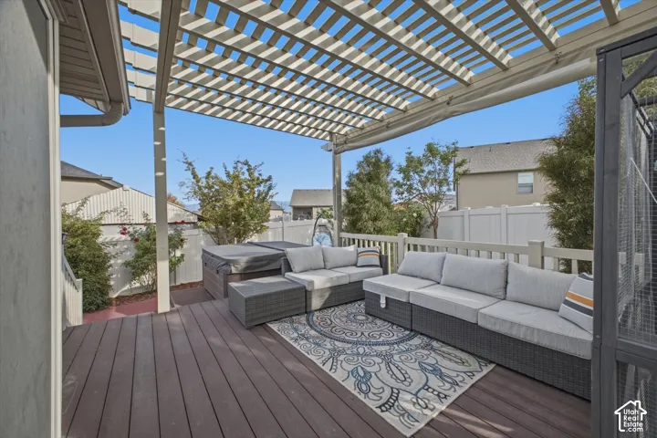 Expansive outdoor deck featuring wood-finish flooring, a slatted pergola, and a privacy fence