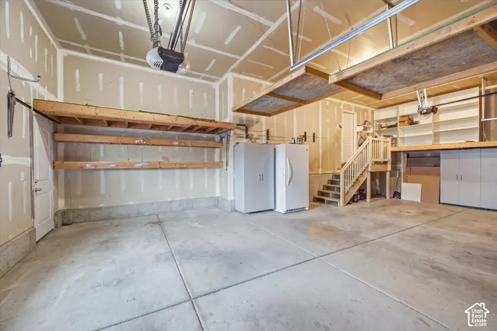 Concrete flooring, built-in shelving, overhead storage, integrated staircase, and dedicated storage cabinetry