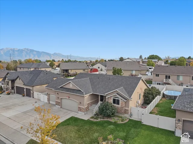 Stucco exterior with stone accents, attached three-car garage, manicured lawn with mature landscaping, and a fenced backyard