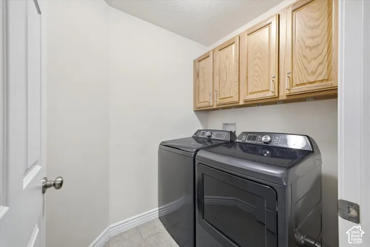 Laundry area featuring wood cabinetry and light-toned flooring