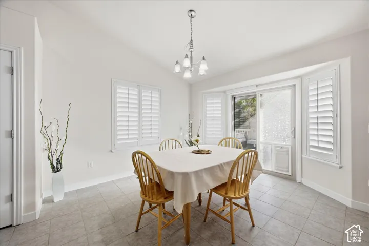 White walls, tiled flooring, pendant light fixture, sliding glass door, and window shutters