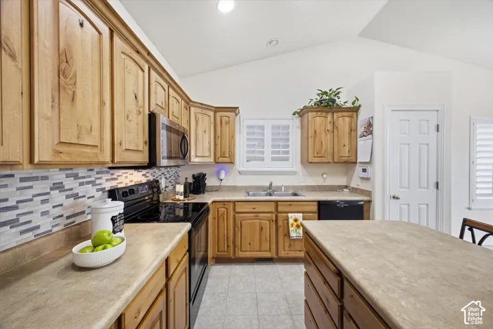 Kitchen featuring natural wood-finish cabinetry, a patterned tile backsplash, and light-toned countertops