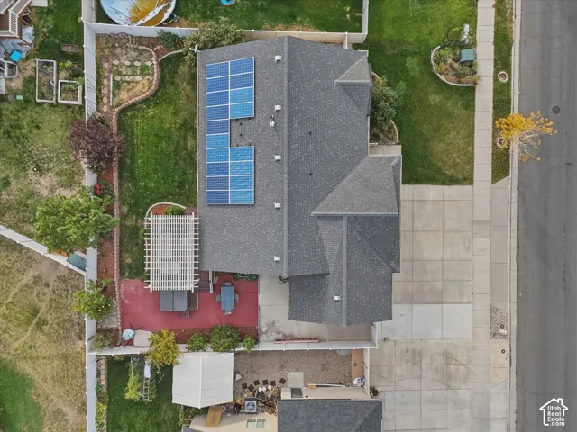 Rooftop solar panels fully paid off with warranty, expansive paved driveway, grey shingle roof, rear patio with pergola, and fenced yard