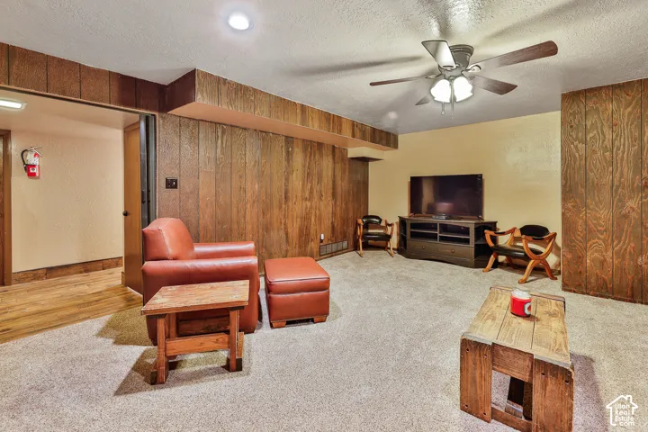 Carpeted flooring, paneled walls, ceiling fan with light fixture, recessed lighting, and an additional doorway