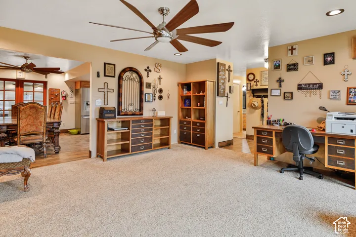 Expansive carpeted living area with a large ceiling fan