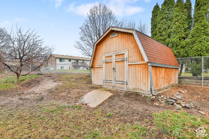 Wood-sided storage shed with a gambrel roof and double doors