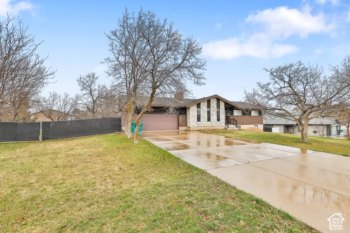 Split-level residence featuring a stone and siding exterior, an attached garage, and a concrete driveway