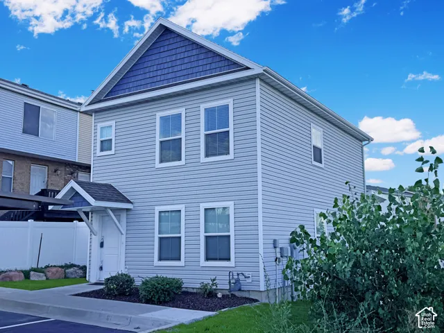 Light gray siding exterior with white window frames, featuring a blue shake-shingle gable accent