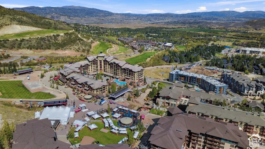 Expansive mountain landscape with multiple residential structures, a large central building with a pool area, and surrounding green spaces