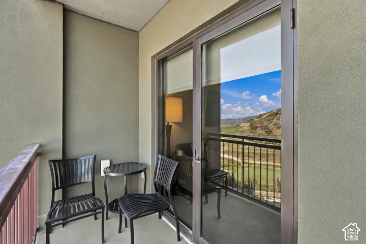 Balcony with a metal railing, featuring a sliding glass door and stucco exterior