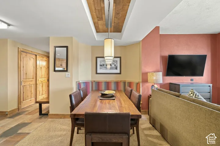 Wood-finish flooring with an area rug, built-in dining bench, wood-paneled ceiling accent, and sliding wood doors