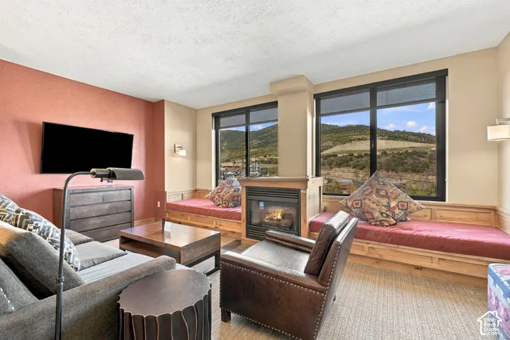 Fireplace with wood surround, wall-mounted television, built-in window seating, and mountain scenery