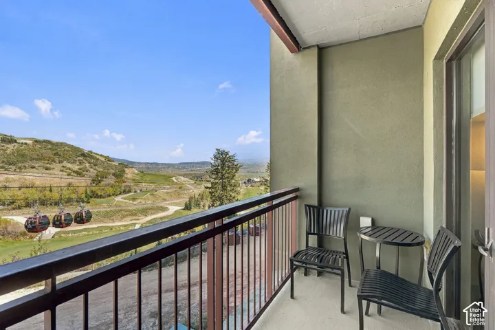 Private balcony with a metal railing, featuring a stucco-finish exterior wall and a glass-paneled door