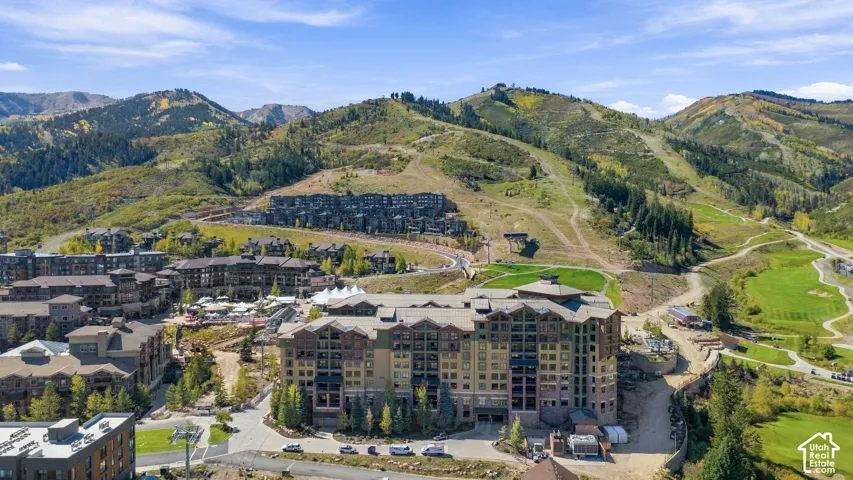 Expansive multi-story property with stone and wood-paneled exterior construction, surrounded by mountainous terrain and a golf course
