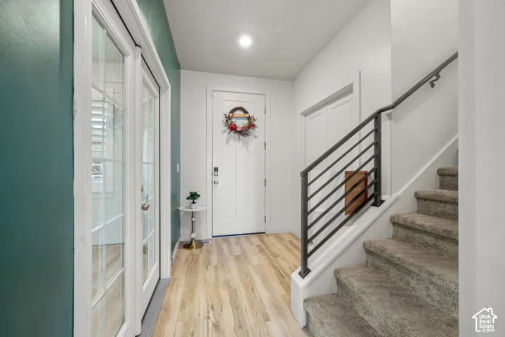 Entryway featuring wood-finish flooring, white paneled doors, and a staircase with a horizontal bar railing