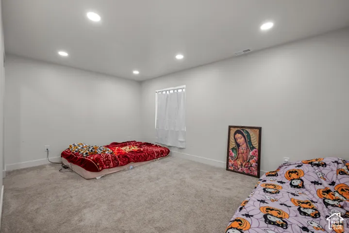 Neutral wall paint, recessed lighting, window with blinds, and carpet flooring