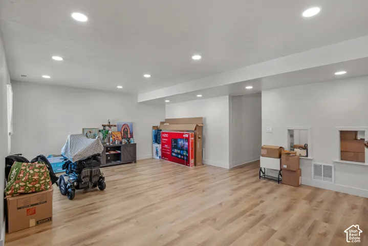 Spacious room featuring recessed lighting, wood-finish flooring, white walls, and a built-in wall niche