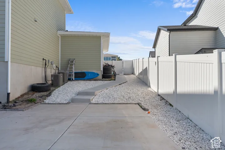 Concrete drive with a white vinyl fence, gravel landscaping, and exterior siding