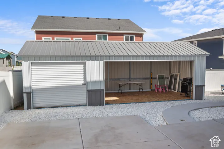 Detached structure with a metal roof and panel siding, featuring a roll-up door and an open bay