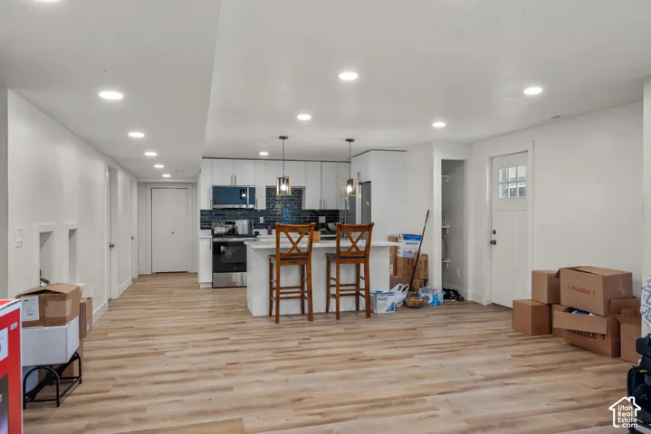 Open concept living space with wood-finish flooring, recessed lighting, and a modern kitchen