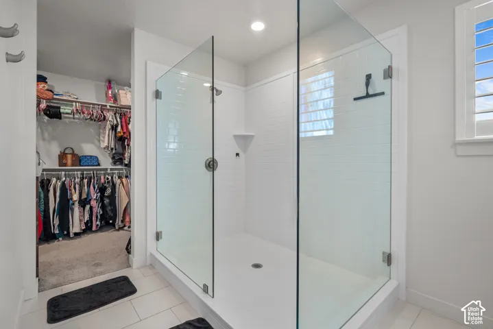 Glass-enclosed shower with white subway tile, a window with louvered shutters, and a recessed light